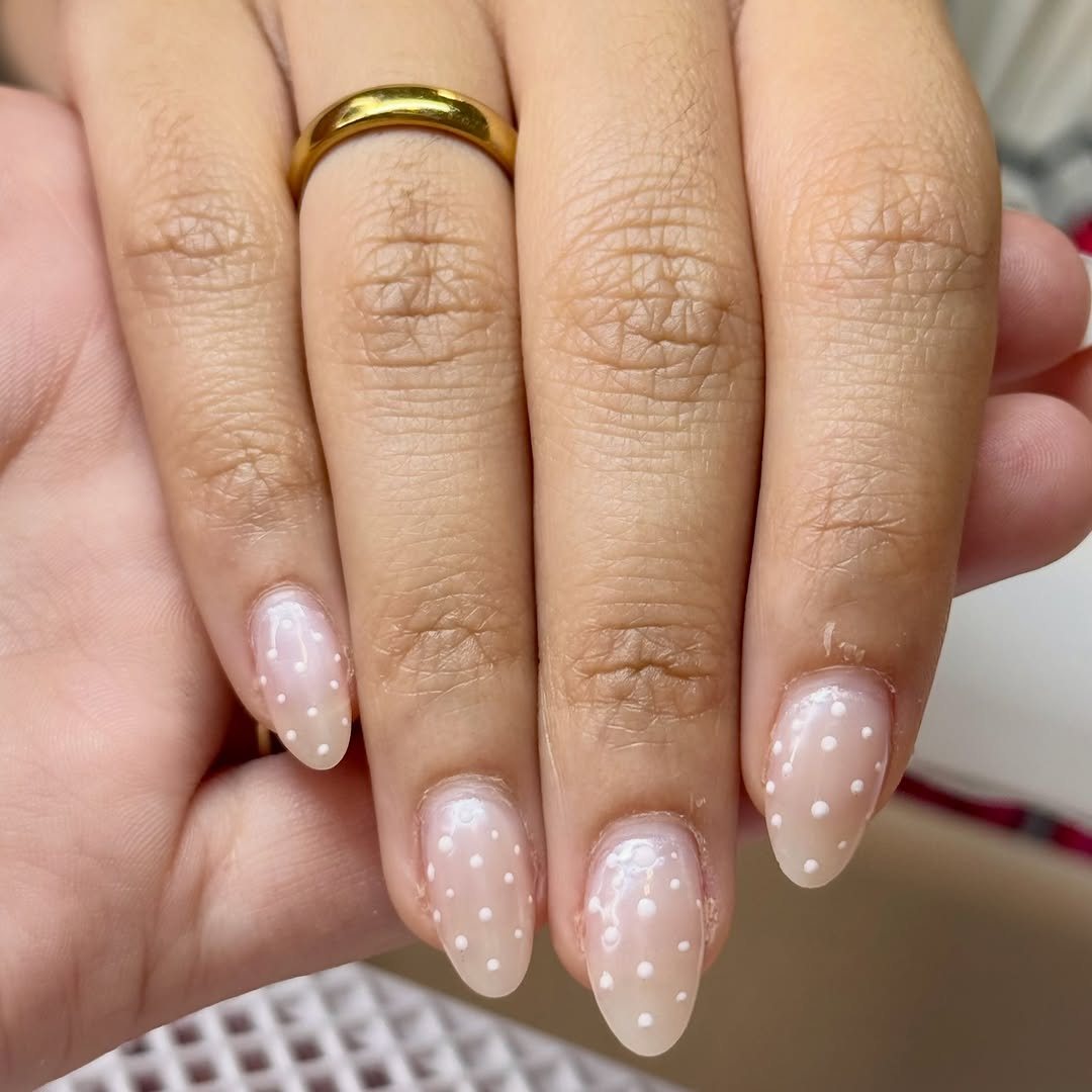 Unhas em tom nude com poás brancos