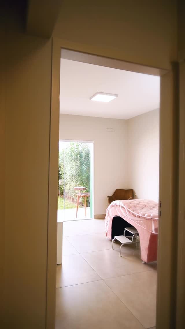 Sala de atendimento do Espaço Oásis, clara, com maca rosa e porta de vidro para o jardim